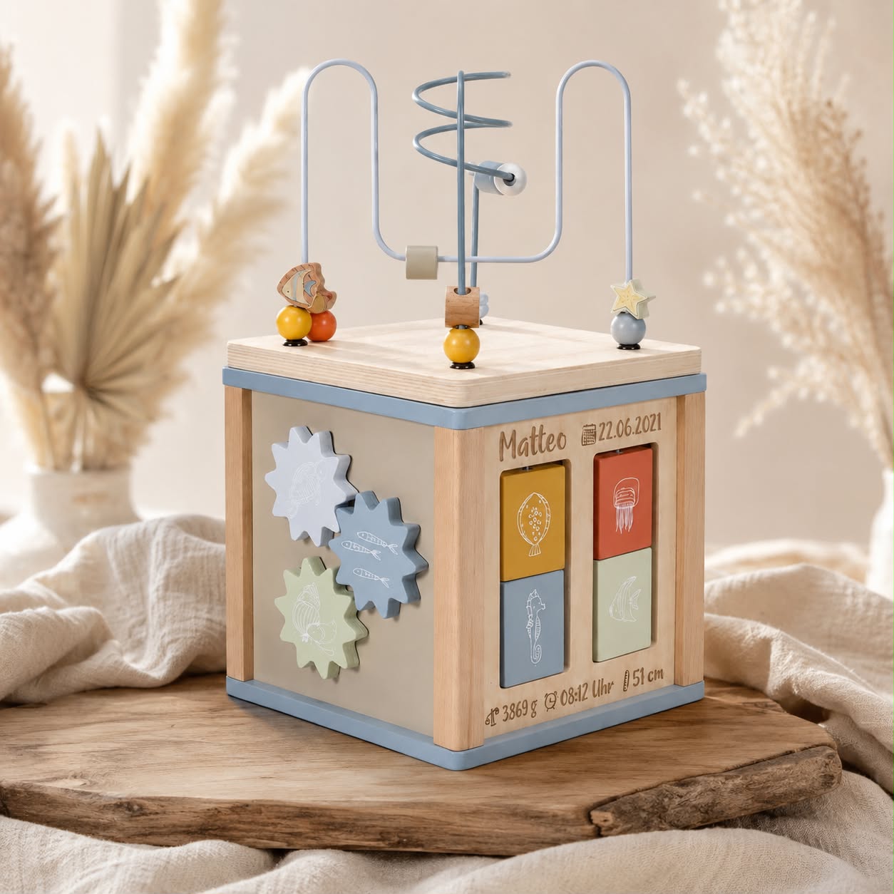 Personalisierter Motorikwürfel mit Geburtsdaten im Boho-Stil auf rustikalem Holzbrett mit Leinentuch und Pampasgras – hochwertiges Geschenk zur Geburt oder Taufe von Schmatzepuffer