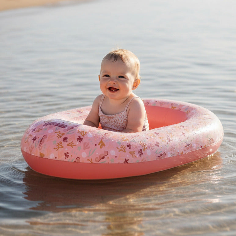 Baby sitzt im rosa Schlauchboot im Wasser – aufblasbares Kinderboot für sicheren Badespaß im Sommer