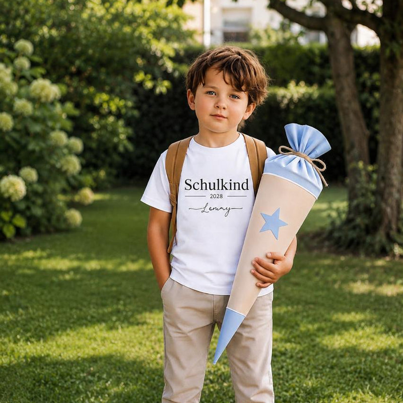 Junge trägt personalisiertes Schulkind T-Shirt 2028 mit Namen Lenny und blauer Schultüte im Garten